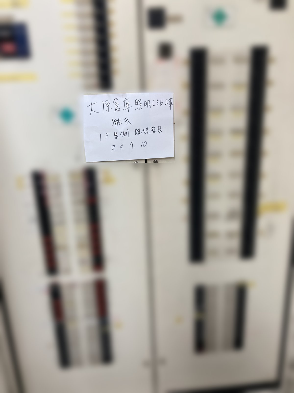 分電盤に貼った手書きメモと一緒に撮った工事写真。工事名・工種・撮影箇所・日付の4行。掲載用に盤のラベルをぼかしている